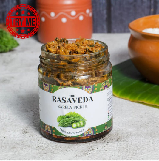 A jar of The Rasaveda Karela Pickle on a light gray stone surface, with a red 'TRY ME' badge overlay in the top left corner.